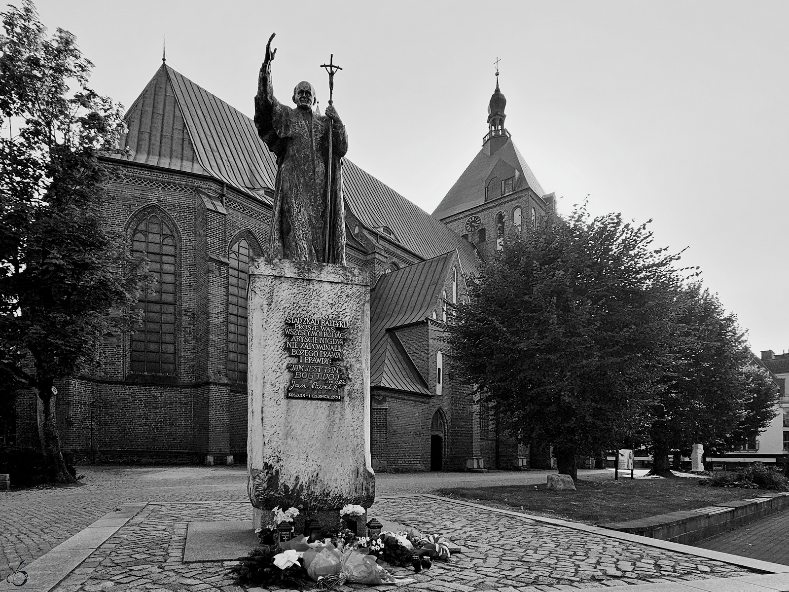 Dieses Denkmal des Papstes Johannes Paul II steht vor der Anfang des 14. Jahrhunderts erbauten Kathedrale Mari Unbefleckte Empfngnis (polnisch Katedra Niepokalanego Poczęcia Najświętszej Maryi Panny w Koszalinie), so gesehen Anfang September 2024 in Koszalin (Kzlin).