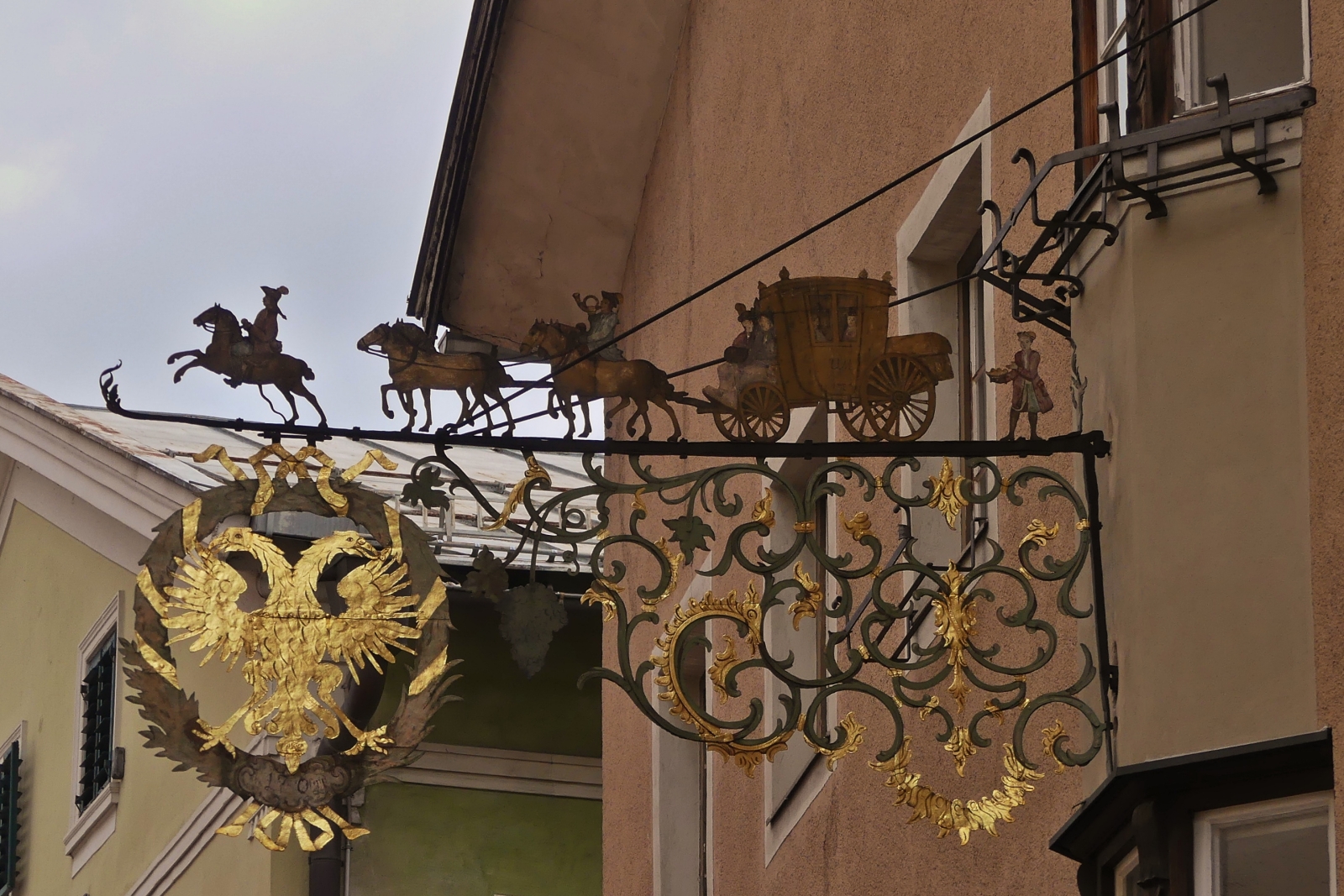 Eisernes Relief mit einer Postkutsche einer Hauswand in Schwaz. 08.2024