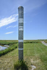 Sturmflutmarkierungspfahl auf der Hallig Oland im Nordfriesischen Wattenmeer.