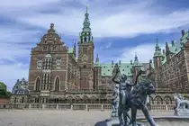 Blick vom �u�eren Schlosshof auf Schloss Frederiksborg in Hiller�d. Das Schloss liegt in einer Abfolge von drei Inseln am westlichen Rand des Schlosssees. Zur Stadt hin wird der Schlossbereich durch eine mit T�rmen und Mauern bewehrte Vorburg gesch�tzt, auf welche die mittlere Insel mit dem �u�eren Schlosshof, dem Kastellanhaus und dem Neptunbrunnen folgt. Auf der letzten Insel liegt das eigentliche Schloss, dessen Mauern direkt aus dem Wasser aufragen.
Aufnahme: 24. Juni 2023.