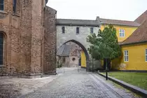 Absalonsbuen am Domplatz von Roskilde. Das Backsteingeb�ude auf der linken Seite ist Teil des Domvon Roskilde. Das gelbe Geb�ude auf der rechten Seite ist Teil des Museums f�r zeitgen�ssische Kunst(d�nisch: Museet for Samtidskunst)  in Roskilde.
Aufnahme: 20. Juni 2023.