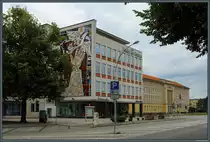 Die Lindenallee (ehemals Leninallee) im WK IV entstand Ende der 1950er Jahre und orientierte sich an der internationalen Moderne. Das ehemalige Kaufhaus Magnet tr�gt heute den Namen Linden-Zentrum. An seiner Seite befindet sich das Wandmosaik  Gemeinschaftsarbeit der sozialistischen L�nder  von 1963. Rechts ist das Rathaus zu sehen. (Eisenh�ttenstadt, 05.08.2023)