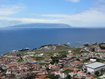 Der Ort Vila do Corvo, mit Flughafen, auf der Azoren-Insel Corvo am 20.07.2024. Hinten die Nachbarinsel Flores.