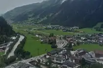Blick aus einer Gondel der Penkelbahn auf Mayrhofen, mit in der Mitte des Bildes dem Bahnhof der Zillertalbahn. 08.2024