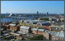 Der Zentralmarkt von Riga wurde 1930 als Markthalle f�r Lebensmittel aller Art errichtet. Davor sind ein paar �ltere Speicher zu sehen, dahinter der Fluss D�na. (Riga, 29.08.2024)