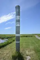 Sturmflutmarkierungspfahl auf der Hallig Oland im Nordfriesischen Wattenmeer. Aufnahme: 1. Juli 2025.