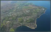 Die 10.000-Einwohner-Stadt Gourock liegt am Ufer des Firth of Clyde westlich von Glasgow. Unten mittig sind der Bahnhof und das F�hrterminal zu sehen, etwas oberhalb der Tower Hill. Weiter landeinw�rts sticht in der linken Bildh�lfte vor allem das dunkle Geb�ude des Inverclyde Royal Hospital heraus. (08.05.2025)