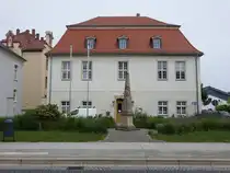 Radeburg, Postmeilens�ule von 1728 und Geb�ude des Bauamts in der Heinrich Zille Stra�e (10.06.2025)