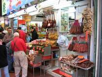 Hong Kong - Szenen auf einem Strassenmarkt zwischen Hopewell Center und Hennessy Rd. Ein Potpourri exotischer D�fte und Speisen... platte Enten, platte H�hner, W�rste, Trockenfisch, getrocknete Enten und H�hner. Das gibt sicher ein leckeres Essen f�r den herren im roten Pullover und f�r sie Familie im Hintergrund.