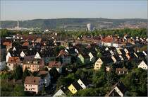 Blick von der Einsteinstra�e aus �ber die durch die Morgensonne angestrahlten H�user von Bad Cannstatt zu den bewaldeten H�ngen der Stadt Stuttgart mit den drei T�rmen (in der Mitte der Fernmeldturm auf dem Frauenkopf und rechts der ber�hmte Fernsehturm auf dem Hohen Bopser). Ganz links kann das silbern schimmernde Daimler-Museum noch erkannt werden, daneben das Daimlerstadion vor dem Kraftwerk Gaisburg. Rechts unterhalb die markante Aufstockung der Maybach-Schule. Rechts der Bildmitte der Gaskessel von Gaisburg. 2.5.2007 (Matthias)