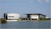 Moderne Architektur und eine Landschaftsgestaltung mit viel Wasser bietet die sehenswerte Autostadt Wolfsburg. Auf diesem vom Mittellandkanal aus aufgenommenen Foto sind links das ZeitHaus und rechts das KonzernForum zu sehen, entworfen von  Henn Architekten . Aufnahmedatum: 29.09.2006