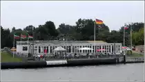 Rendsburg. Die Schiffsbegr��ungsanlage f�r die den Nord-Ostsee-Kanal passierenden Schiffe ist direkt neben der Hochbr�cke in dem kleinen runden Pavillon vor dem Caf� & Restaurant  Br�ckenterrassen  angesiedelt. Dies Foto entstand von der Schwebef�hre. 04.09.2012