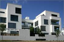 Wohnanlage  Rosenpark  in Stuttgart. Die Geb�ude wirken einerseits vielf�ltig und abwechslungsreich durch die Vor- und R�ckspr�nge der kubischen Bauformen und die versetzt angeordneten gro�fl�chigen Fenster. Einheitlichkeit entsteht durch die wenigen Materialien: wei�er Putz, mit Licht- und Schattenwirkung unterbrochen lediglich durch die dunklen Glasfl�chen. F�r mein Empfinden eine gestalterisch sehr gelungene Anlage. 30.5.2007 (Matthias)