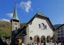 Zermatt, Pfarrkirche St. Mauritius. Westfassade mit abgewalmtem Dach und Rundbogen, links der flankierende Chorturm. 1910-1913 nach Pl�nen von Adolf Gaudy aus Rorschach realisierter Bau anstelle der kleineren, aus dem Mittelalter stammenden Vorg�ngerkirche. 1925 wurde die Turmuhr installiert, w�hrend die 3 neuen Glocken 1932 aufgezogen wurden. Aufnahme vom 13. Okt. 2011, 15:48
