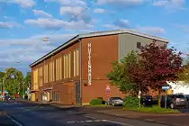 Das H�ttenhaus in Herdorf am 11.05.2013.
Das H�ttenhaus wurde 1953 von der damaligen Friedrichsh�tte AG errichtet. Durch das Engagement des H�ttendirektors Dipl.-Ing. Heinz Berndt baute das Unternehmen ein Belegschaftshaus, welches diversen Belangen aller Mitarbeiter dienen sollte. So entstand das  H�ttenhaus  und erm�glichte der Belegschaft Theatervorstellungen und Musikdarbietungen zu besuchen. 
Bis heute sind bekannte Schauspielh�user und viele ber�hmte deutschsprachige Darsteller agiert auf der B�hne des H�ttenhauses und machen es weit �ber die Grenzen der Stadt Herdorf bekannt. 
1968 wurde die Friedrichsh�tte geschlossen und um es als kulturellen Mittelpunkt f�r die Region zu erhalten, erwarb die Stadt Herdorf das H�ttenhaus. 
