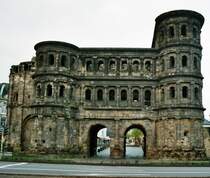 Die Porta Nigra ist das n�rdliche Stadttor der R�merstadt. Verwitterund, Ru� und Staub lie�en die die Steine im Laufe der Jahrhunderte schwarz werden und gaben dem Bauwerk die Bezeichnung  Porta Nigra  (Schwarzes Tor).
Die Porte mit ihrer palastartigen Architektur ist nicht nur Wahrzeichen Triers, sondern dar�ber hinaus machtvolles Symbol der Begegnung zwischen R�mern, Kelten und Germanen. Denn durch das Tor verlief die Ausfallstra�e zum Rhein in die germanischen Provinzen. Umgekehrt m�ndete in das Nordtor vom Stadtinneren her die nords�dliche Hauptstra�enachse, der cardo maximus, dessen Verlauf in der Simeonstra�e noch weiterlebt.