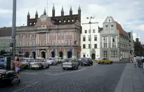 Rostock am 1. Juli 1990: Ernst-Th�lmann-Platz, seit 1991 wieder Neuer Markt, mit dem Rathaus. Nur das oberste Teil des Rathausgeb�udes zeigt dem Betrachter, dass der urspr�ngliche Bau (aus dem 13. Jh) ein Backsteingeb�ude war. Anstelle der Laube aus dem Mittelalter errichteten Zacharias Voigt und Joseph Petrini 1727 - 1729 einen dreigeschossigen Barockvorbau. - Ganz rechts ahnt man das Kerkhofhaus (An der Hege / Ecke Grosse Wasserstrasse), ein Backsteinhaus, das f�r den B�rgermeister Kerkhof um 1470 erbaut wurde.