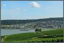 Blick von den Weinbergen bei R�desheim auf die Stadt Bingen. Hier beginnt das Mittelrheintal, das f�r seine zahlreichen Burgen bekannt ist. Ein Frachtschiff verl�sst diesen Abschnitt nun und setzt seine Fahrt weiter rheinaufw�rts fort, um in K�rze Wiesbaden und Mainz zu passieren. (aufgenommen aus der Seilbahn R�desheim, 09.08.2014)