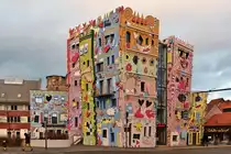 . Braunschweig - Das Happy RIZZI House am Ackerhof. 04.01.2015 (Hans)

Am Rande des historischen Magniviertels liegt seit 2001 das vom international bekannten New Yorker K�nstler James Rizzi gestaltete Happy RIZZI House. Es wurde in zweij�hriger Bauzeit auf Initiative des Galeristen Olaf Jaeschke und des Architekten Konrad Kloster verwirklicht. Die lachenden, bunten H�usert�rme sind als dreidimensionaler Bauk�rper realisiert und pr�sentieren sich als begehbare Bauskulptur. Der Bau wird heute als B�rohaus genutzt und ist nicht �ffentlich zug�nglich.

Das Geb�ude ist mit Pop-Art-Malereien gestaltet. H�ufigstes Motiv an der Fassade sind die fr�hlichen Gesichter. Dar�ber hinaus findet man weitere wiederkehrende Motive wie u.a. Herzen, Augen, Sterne und V�gel.

In der Reihe  Die sch�nsten Bauwerke Deutschlands  der Zeitschrift H�rzu wurde das Rizzi-Haus per Leserwahl zu einem der 100 sch�nsten Bauwerke gew�hlt.
