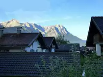 Garmisch-Partenkirchen, Blick am fr�hen Morgen �ber die D�cher von Partenkirchen zum sonnenbeschienenen Zugspitzmassiv, Aug.2014