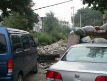 Immer wieder beeindruckend f�r Touristen, w�hrend Chinesen sich wundern (und auch manchmal �rgern), dass man so etwas fotografiert. Moderner Fuhrpark in heruntergekommenen Ecken, ein h�ufiger Kontrast. 09/2007, Peking