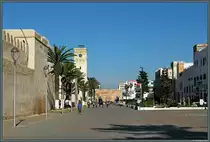 Eine Besonderheit der Medina von Essaouira ist das rechtwinklige Stra�ennetz. Eine der Hauptstra�en ist die Avenue Oqba Ibn Nafiaa, die auch das Stadttor Bab Moulay Youssef im Hintergrund durchquert. Links ist ein Teil der Stadtmauer zu sehen. (Essaouira, 21.11.2015)