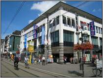 Die zentrale Fu�g�ngerzone von Neuss mit einem modernen Konsumtempel. Durch diese Stra�e f�hrt die Stra�enbahnlinie 709 der D�sseldorfer Rheinbahn, die eine direkte Anbindung an das D�sseldorfer Stadtzentrum mit der K� bietet. 2007 gab es eine B�rgerabstimmung zu der Frage, ob die Stra�enbahn aus der Fu�g�ngerzone herausgenommen werden soll. Dies fand jedoch keine Mehrheit. (03.08.2007)