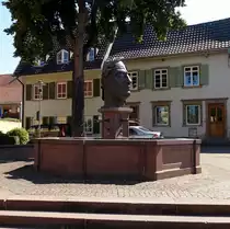 Riegel, Brunnen mit R�merkopf am Brunnenplatz an der Hauptstra�e, Aug.2015 