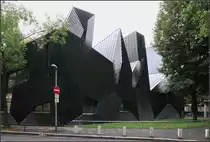 . Ungw�hnlich -

... in Form, Farbe und Material, die neue Synagoge in Mainz. Geplant von Manuel Herz, eingeweiht im Jahr 2010.  Hier ein Link zu einer Meldung im Baunetz, wer den Bau besser verstehen will:

https://www.baunetz.de/meldungen/Meldungen-Synagoge_von_Manuel_Herz_in_Mainz_eingeweiht_1297777.html

Leider war bei unserem Besuch recht tristes, nasses Wetter, aber trotzdem oder vielleicht gerade aufgrund der N�sse kommen die Lichtreflexionen auf der Metal- und Keramikfassade sch�n zur Geltung.

12.08.2017 (M)