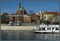 Am Petrif�rder liegt der Anlieger der Magdeburger Wei�en Flotte, deren Fahrgastschiffe (u.a. die  Wolfsburg ) zu verschiedenen Rundfahrten auf der Elbe unterwegs sind. Im Hintergrund ist die aus dem 13. Jahrhundert stammende Wallonerkirche zu sehen. Dieser Teil Magdeburgs geh�rte zum sogenannten  Knattergebirge , einst eine der am dichtesten bebauten Wohngebiete Europas, das im 2. Weltkrieg allerdings weitgehend zerst�rt wurde. (Magdeburg, 30.03.2018)