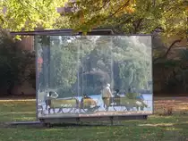 Hamburg am 11.10.2018: Spiegelungen im „Double Triangular Pavilion for Hamburg“ des K�nstlers Dan Graham, in der Parkanlage „Uhlenhorster F�hrhaus“ an der Au�enalster, die zu sehenden Menschen sitzen am Alsterufer /