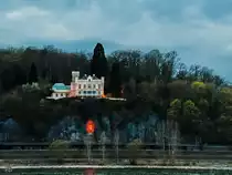 Das neugotische Schloss Marienfels und darunter eine angeleuchtete halbrunde Grotte, in der eine Mutter-Gottes-Figur aufgestellt wurde. (Remagen, April 2021)