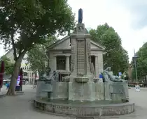 Hamburg am 1.8.2021: Der M�nckebrunnen und das dahinter liegende Geb�ude wurden vom damaligen Oberbaudirektor Fritz Schumacher entworfen und 1926 fertiggestellt. Die Bronzen stammen aus der Werkstatt des K�nstlers Georg Wrba. Das Geb�ude mit den S�ulen war eine �ffentliche B�cherhalle und wurde 2009 in ein Kulturcaf� umgewandelt. Das Ensemble entstand zum Gedenken an den Hamburger B�rgermeister Johann Georg M�nckeberg (1839-1908)