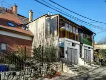 Dieses Foto habe ich in P�cs, in der Stadtteil  Erzs�bettelep  (Elisabethsiedlung) gemacht. Dieser Stadteil wurde durch die Donaudampfschiffgesellschaft gegr�ndet. Die  Kolonie  stand aus 4 Strassen und 32 H�user. Es gab 6 kleine Wohnungen pro Haus zzgl Gartenteil und Nebengeb�ude. Vor ca. 100-120 Jahren wurden neue Kohlenminien in der N�he er�ffnet und die dort arbeitenden haben hier Wohnungen bekommen. Die Siedlung hie� urspr�nglich Ullmannsiedlung, genannt nach einem Leiter des Unternehmens. 1938 wurde auf Elisabethsiedlung umbenannt (von Elisabeth Amalie Eugenie von Wittelsbach K�nigin genannt). Die H�user waren �berdurchschnittlich ausger�stet, da Leitungswasser und Strom auch vorhanden war. In den vergangenen guten Jahrhundert wurde es nicht geregelt wie man die Geb�uden/Wohnungen �ndern, erweitern, umbauen oder zusammenlegen/vereinigen darf. Deswegen ist auf heutzutage das Strassenbild ganz ganz gemischt (und daher meiner Meinung nach, sehr einzigartig und interessant) geworden. Die Etagen wurden ge�ndert, Dachgeschosse wurden eingebaut...daher findet man hier keine zwei gleiche H�user. Die gro�e �nderungen sind um ca 1926 begonnen. Wegen der damaligen Wohnungsmangel hat die Stadt 2/3-tel der Siedlung in Miete genommen und hat unter anderem eine Kirche und Schule erbaut und ge�ffnet. Aufnahmezeit: November 2020.
Das Haus ohne Vorgarten wurde (letztes mal) anscheinend zwischen den siebzigern und achtzigern erweitert/modernisiert.