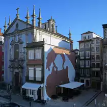 Ein kleines Restaurant, dahinter die St. Nicholas-Kirche (Igreja Paroquial de S�o Nicolau) in Porto. (Januar 2017)