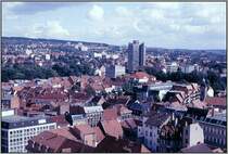 Blick vom einem der T�rme der Johanniskirche �ber die G�ttinger Innenstadt in s�d�stliche Richtung. Im Zentrum des Bildes der Turm des neuen Rathauses. Dieses Bild wurde etwa Mitte der 80er Jahre des vergangenen Jahrhunderts von meinen Vater Alfred Schmidt aufgenommen; es handelt sich um den Scan eines Dias. Seitdem hat es aber keine wirklich gravierenden �nderungen gegeben, die das Stadtbild wesentlich ver�ndert haben.