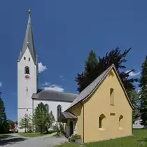 Die katholische Pfarrei St. Johannes Baptist wurde 1872 im neugotischen Stil wiederaufgebaut, nachdem die vorherige Kirche im Jahre 1865 durch einen Brand gr��tenteils zerst�rt worden war. Das Geb�ude im Vordergrund ist die Seelenkapelle. (Oberstdorf, AJuli 2017)